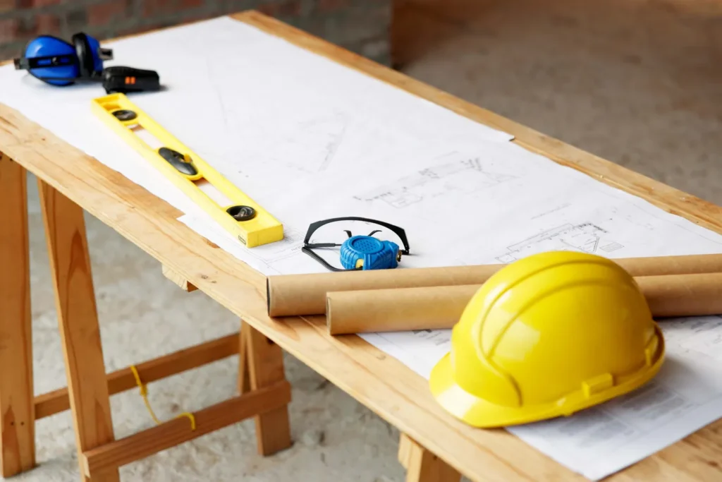 Plans de construction, casque jaune, niveau et outils sur un établi en bois